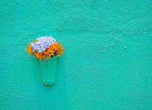 Turquoise wall with vase of blue and orange flowers