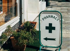 Sign with the word pharmacy in green with a cross and an arrow